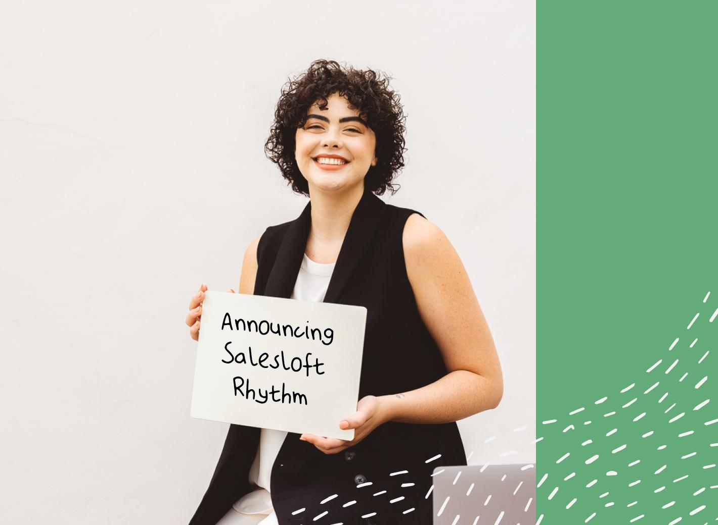 Employee smiling with a sign that says, "Announcing Salesloft Rhythm"